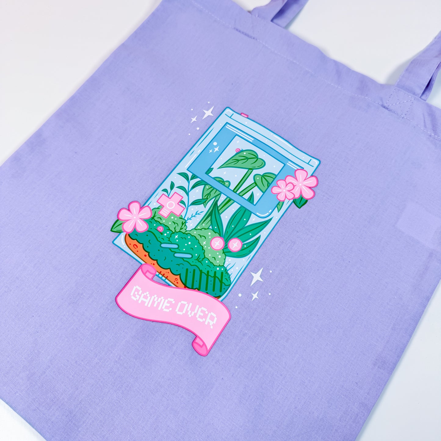 Purple tote bag with a plant-themed design and 'Game Over' text on a white background