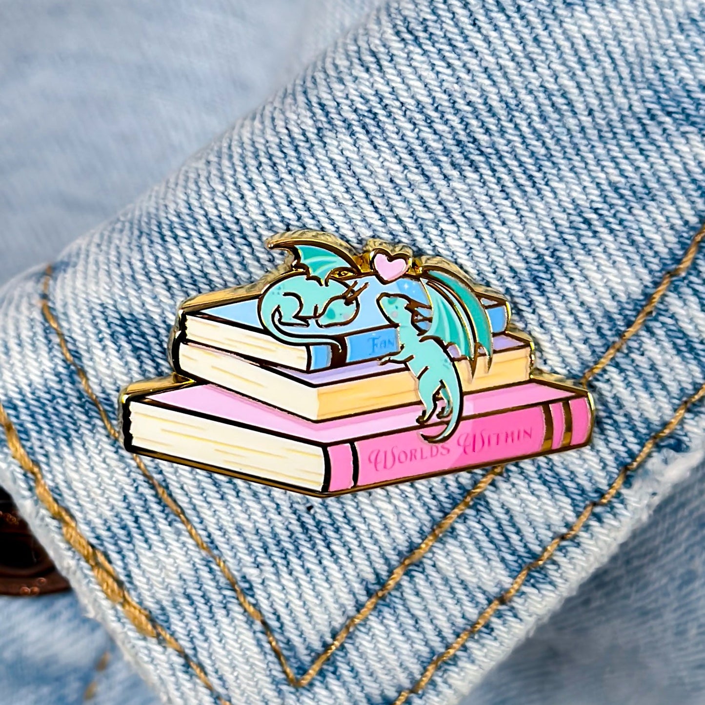 Pin with a dragon on books on a denim background