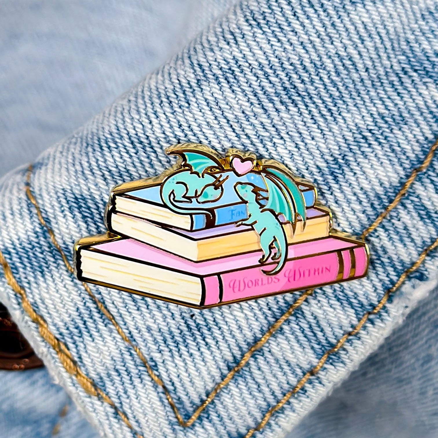 Pin with a dragon on books on a denim background