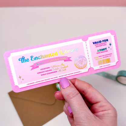 Hand holding a pink and white ticket-like bookmark with holographic foil