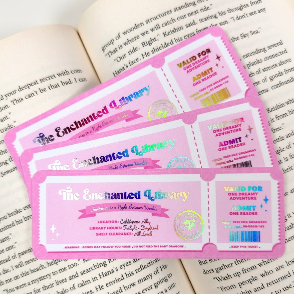 Three 'The Enchanted Library' tickets on an open book