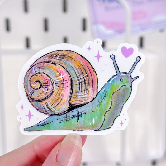 Colorful snail sticker held by a hand against a white background
