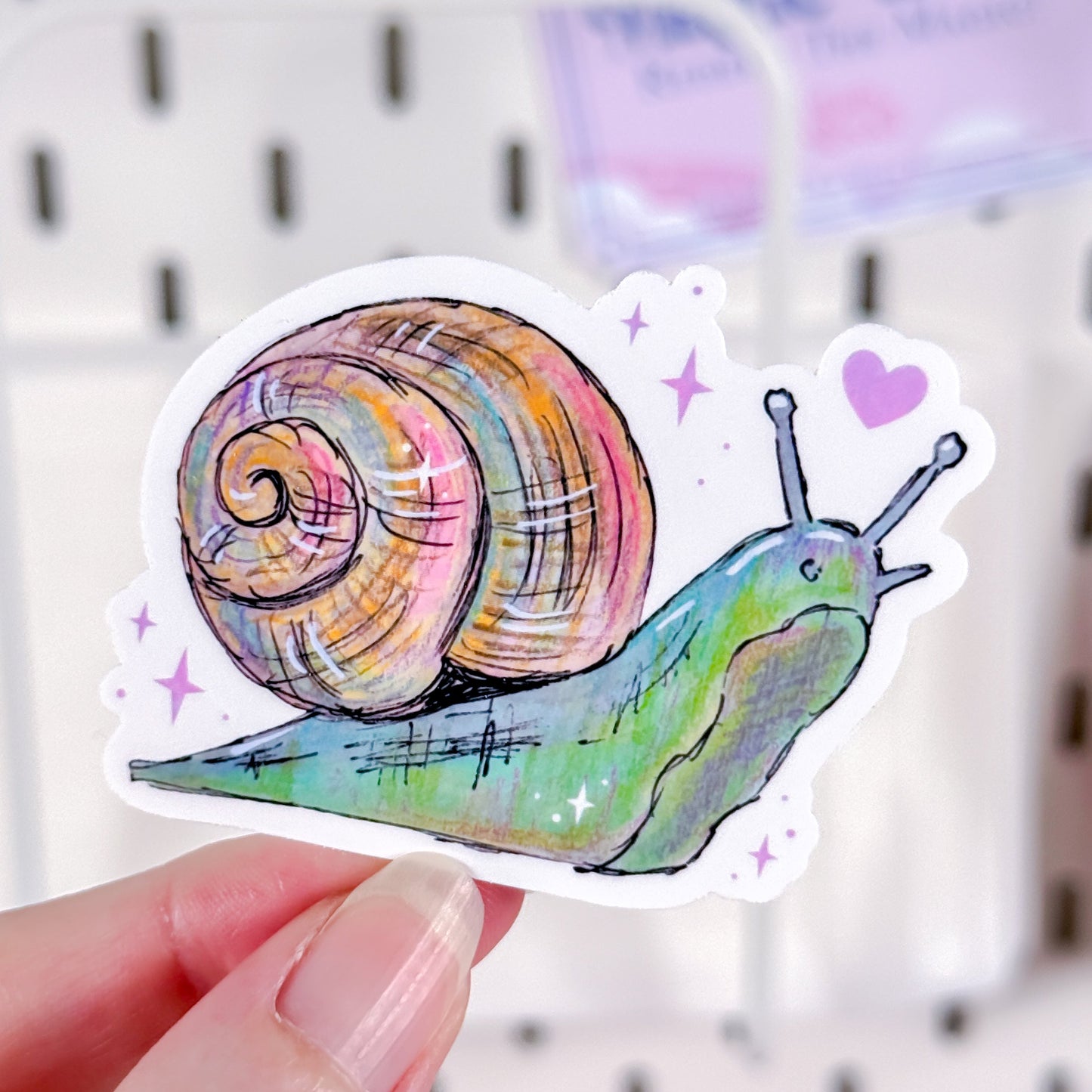Colorful snail sticker held by a hand with a white background